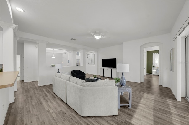 living room featuring visible vents, a ceiling fan, arched walkways, and light wood finished floors