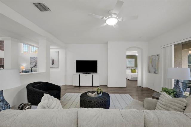 living room with ceiling fan, wood finished floors, visible vents, and arched walkways