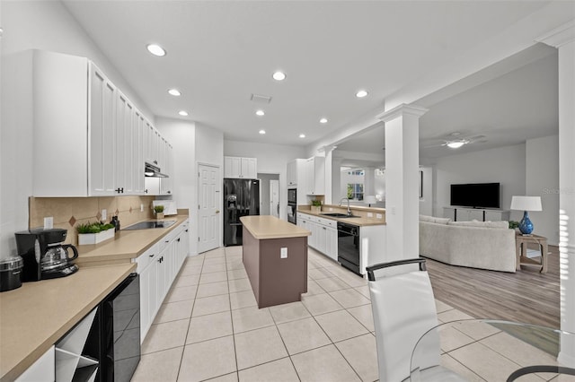 kitchen featuring black appliances, light tile patterned flooring, a kitchen island, and a sink