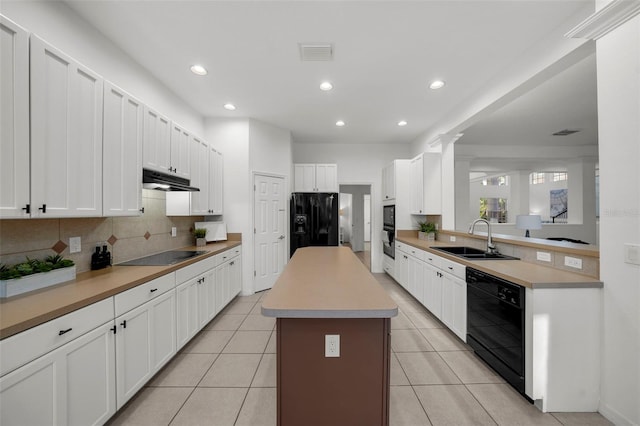 kitchen featuring visible vents, a center island, under cabinet range hood, black appliances, and a sink