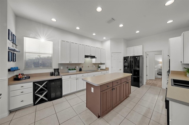 kitchen with visible vents, black appliances, white cabinets, under cabinet range hood, and a center island