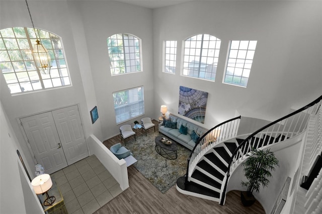 foyer entrance with a high ceiling, an inviting chandelier, wood finished floors, and stairs