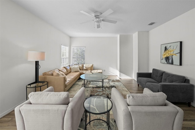 living room with visible vents, baseboards, wood finished floors, and a ceiling fan