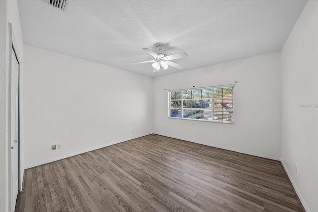 unfurnished room featuring visible vents, baseboards, ceiling fan, and wood finished floors