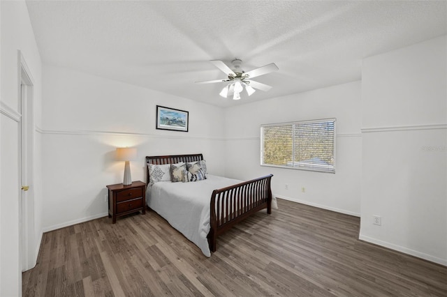 bedroom with ceiling fan, baseboards, a textured ceiling, and wood finished floors