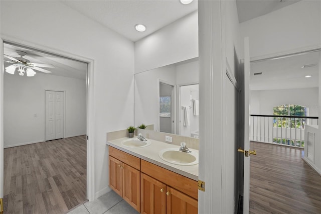 bathroom featuring a sink, double vanity, wood finished floors, and a ceiling fan