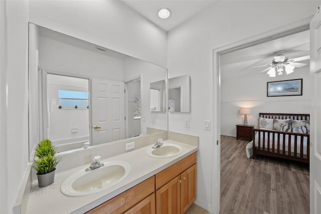 full bath with double vanity, wood finished floors, ensuite bathroom, and a sink