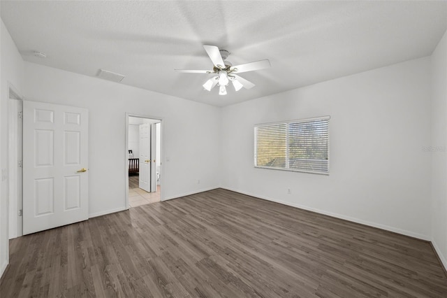 unfurnished room featuring a ceiling fan, wood finished floors, visible vents, and baseboards