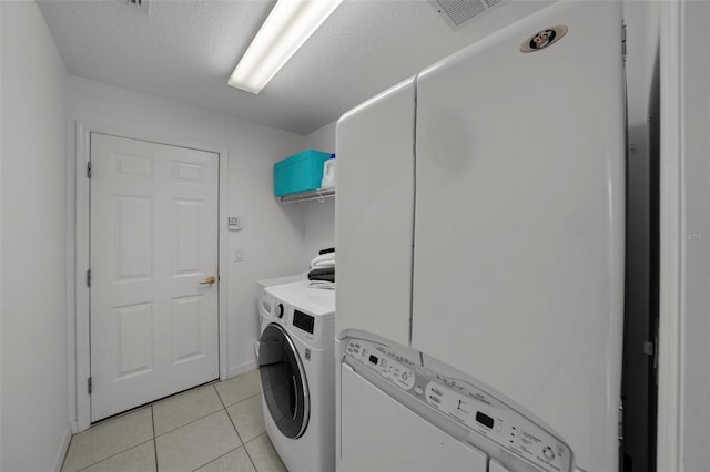 laundry area with visible vents, stacked washer and clothes dryer, a textured ceiling, light tile patterned floors, and laundry area