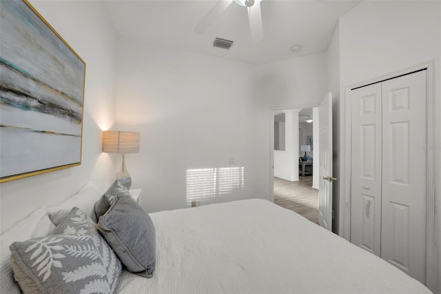 bedroom featuring ceiling fan, visible vents, a closet, and wood finished floors