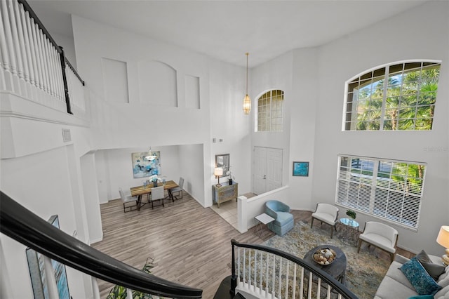 living room featuring visible vents, a healthy amount of sunlight, a high ceiling, and wood finished floors