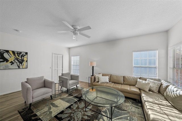 living room featuring a textured ceiling, wood finished floors, baseboards, and ceiling fan