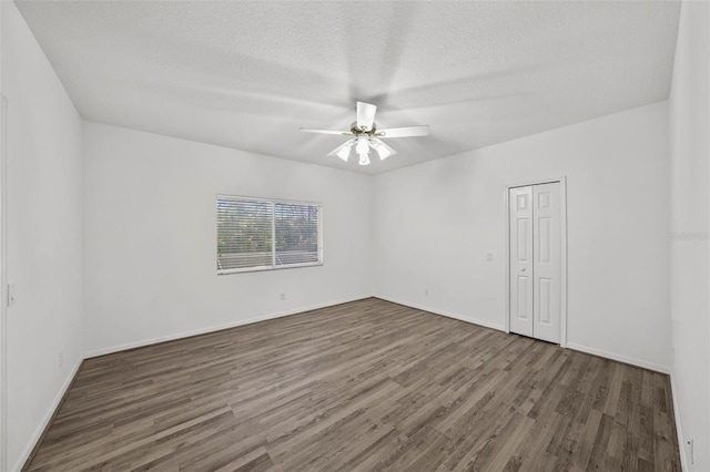 spare room featuring baseboards, a textured ceiling, wood finished floors, and a ceiling fan