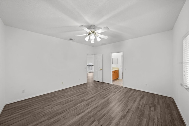 unfurnished bedroom featuring connected bathroom, wood finished floors, visible vents, and baseboards