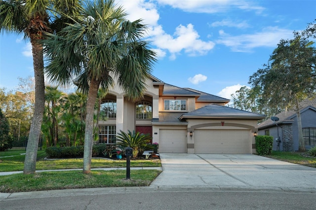 view of front facade featuring a tile roof, a front yard, stucco siding, a garage, and driveway