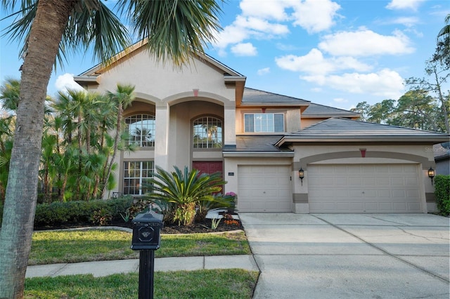 view of front facade with a tile roof, stucco siding, concrete driveway, and a garage