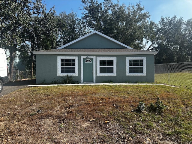 view of front facade with stucco siding, fence, and a front yard