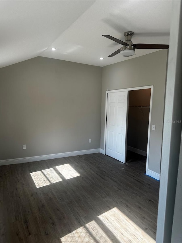 unfurnished bedroom featuring baseboards, dark wood-style floors, ceiling fan, vaulted ceiling, and a closet