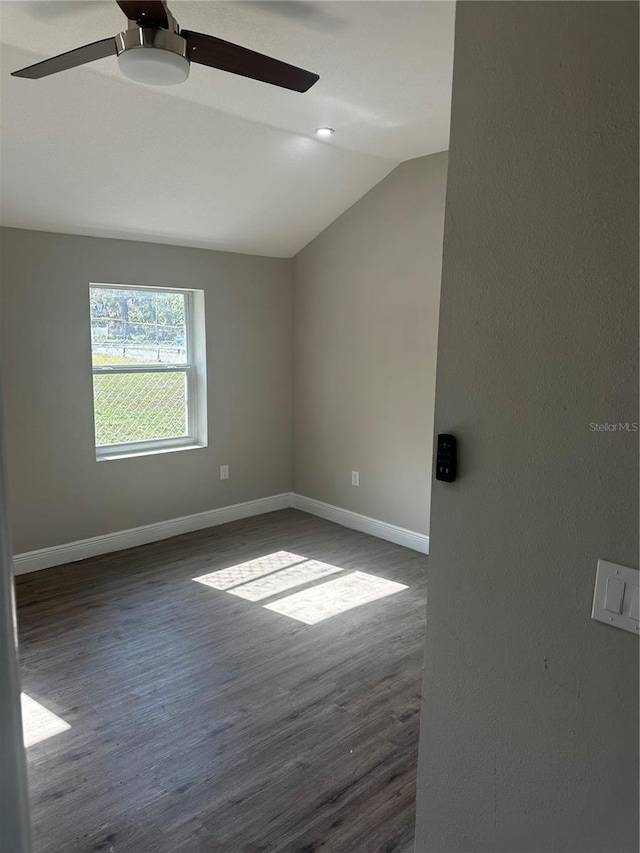 unfurnished room featuring vaulted ceiling, dark wood finished floors, and baseboards