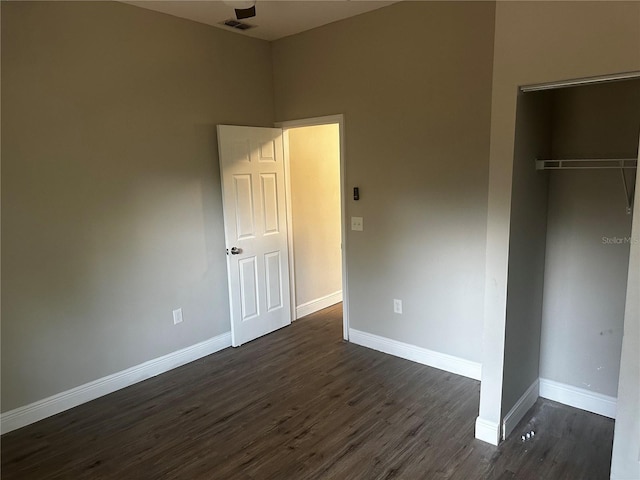 unfurnished bedroom with dark wood-style flooring, a closet, visible vents, and baseboards