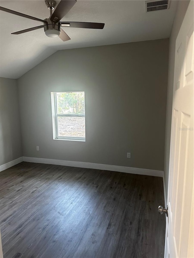 unfurnished bedroom featuring ceiling fan, dark wood-type flooring, visible vents, baseboards, and vaulted ceiling