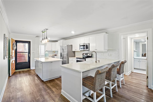 kitchen featuring stainless steel appliances, dark wood-type flooring, a sink, ornamental molding, and a center island