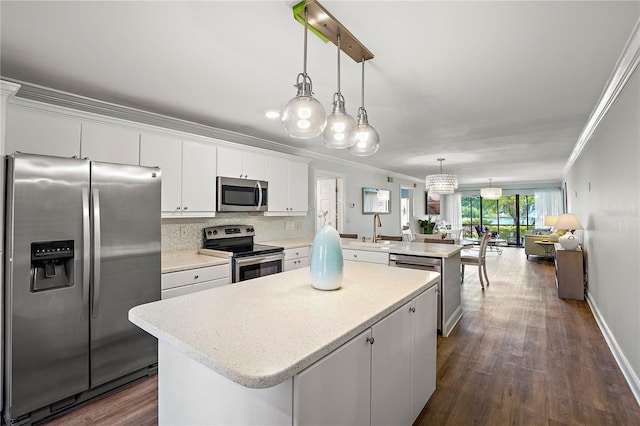 kitchen featuring stainless steel appliances, a peninsula, a kitchen island, light countertops, and ornamental molding