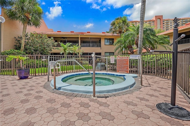 view of swimming pool with fence and a hot tub