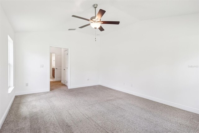 empty room with vaulted ceiling, light carpet, visible vents, and baseboards