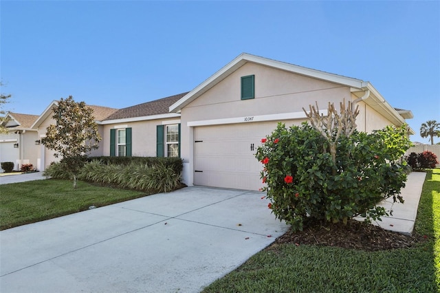 single story home with driveway, a front yard, an attached garage, and stucco siding