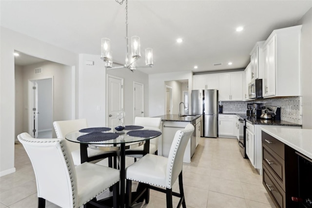 kitchen featuring tasteful backsplash, light tile patterned floors, a center island with sink, and stainless steel appliances