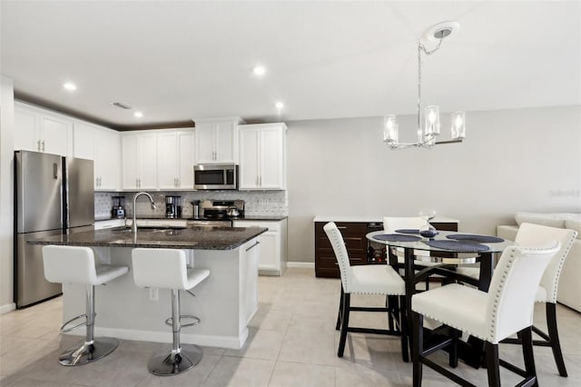 kitchen with a notable chandelier, a kitchen bar, decorative backsplash, stainless steel appliances, and a sink