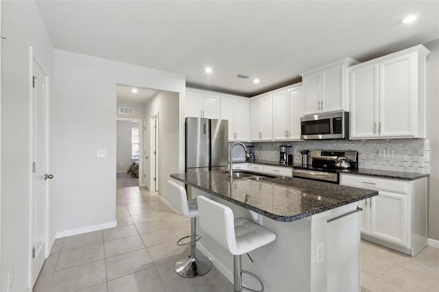 kitchen featuring stainless steel appliances, light tile patterned floors, a sink, and decorative backsplash