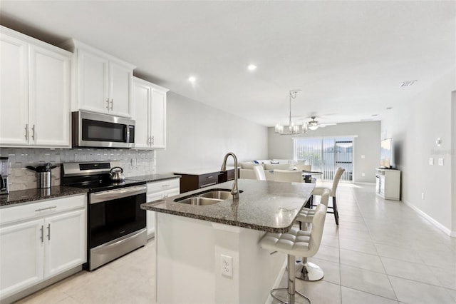 kitchen featuring tasteful backsplash, a sink, an island with sink, dark stone counters, and stainless steel appliances