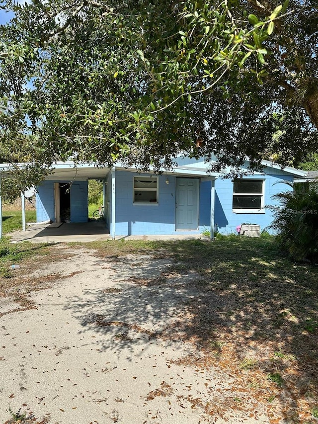 view of front of house featuring driveway, an attached carport, and concrete block siding