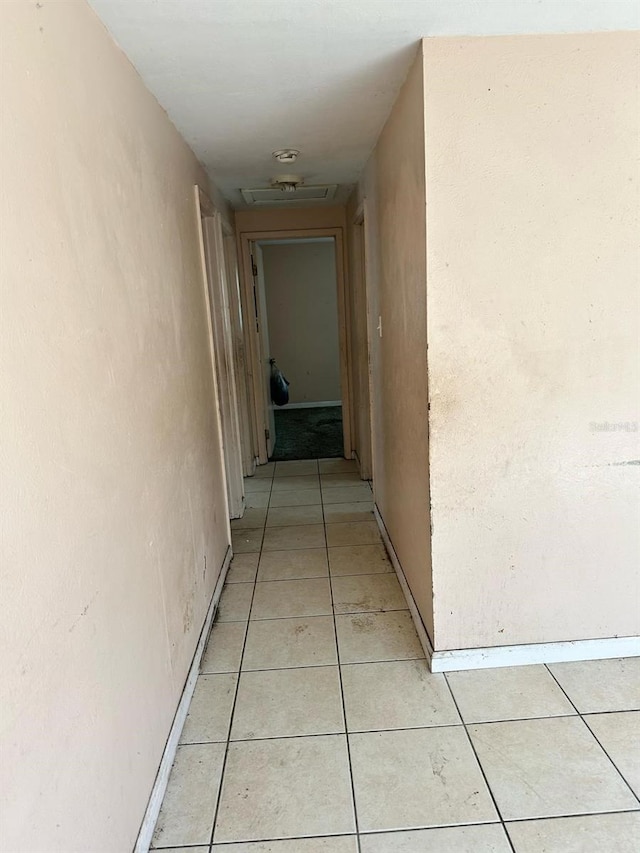 hall featuring attic access and light tile patterned floors