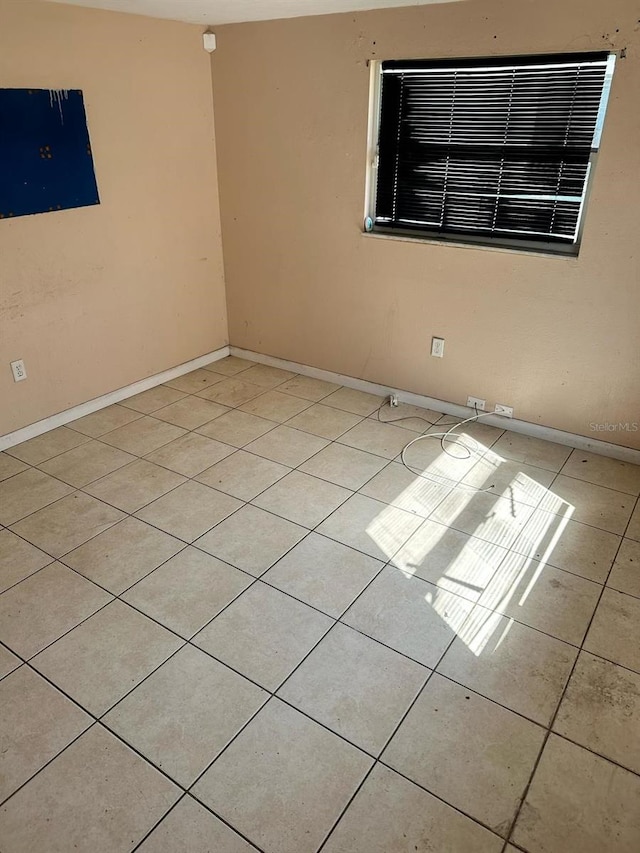 empty room featuring light tile patterned floors and baseboards