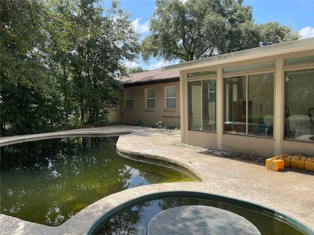 back of property with stucco siding and a sunroom