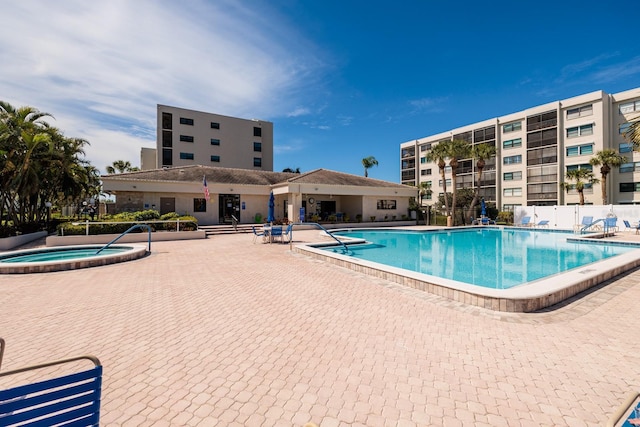 community pool featuring a hot tub, a patio, and fence