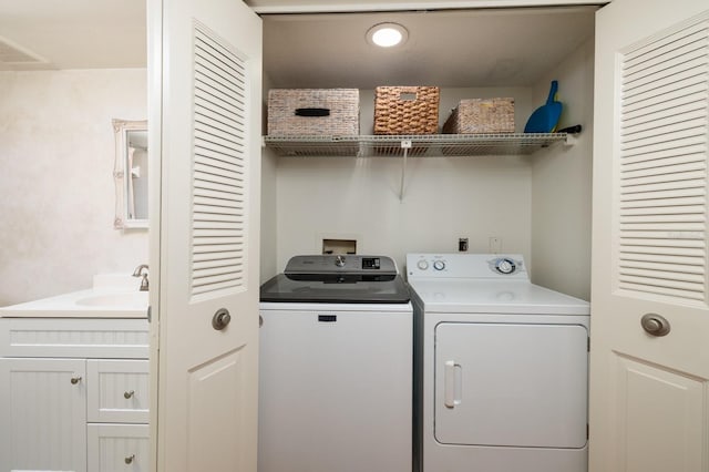 clothes washing area with washer and dryer, laundry area, and a sink