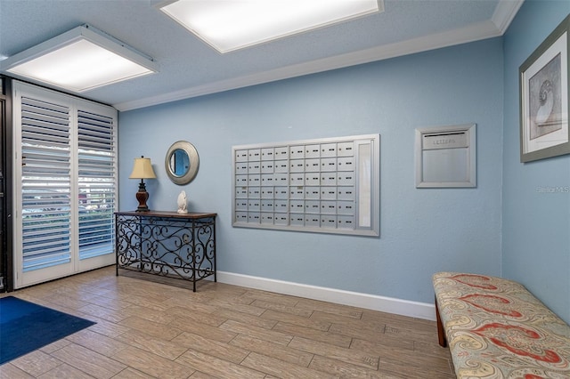 interior space with mail area, crown molding, baseboards, and wood finished floors