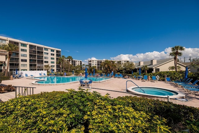 pool featuring a patio area, a community hot tub, and fence