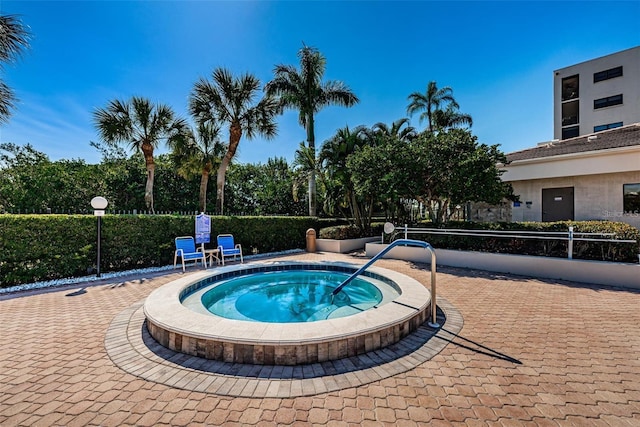 view of swimming pool featuring a community hot tub and fence