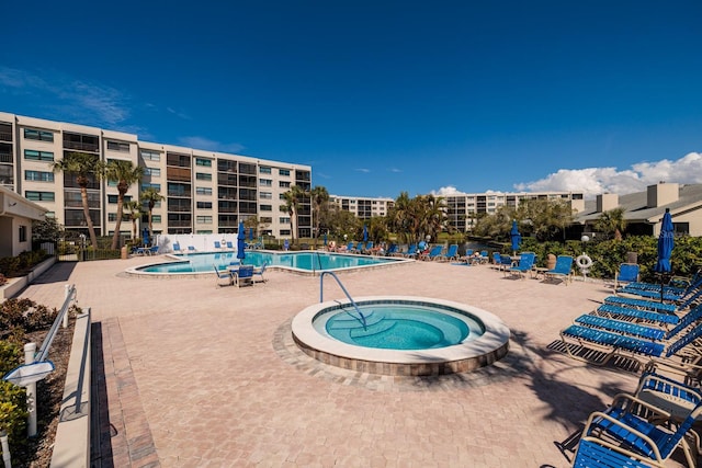 pool with fence, a community hot tub, and a patio area