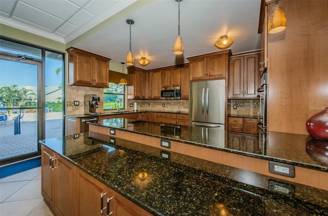 kitchen with light tile patterned floors, brown cabinets, appliances with stainless steel finishes, and backsplash