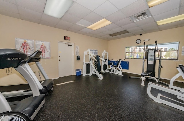 exercise room with a drop ceiling, visible vents, and baseboards