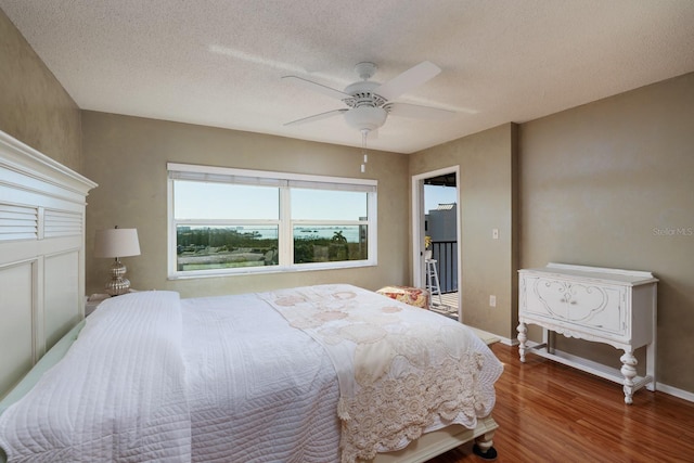 bedroom featuring a textured ceiling, a ceiling fan, baseboards, and wood finished floors