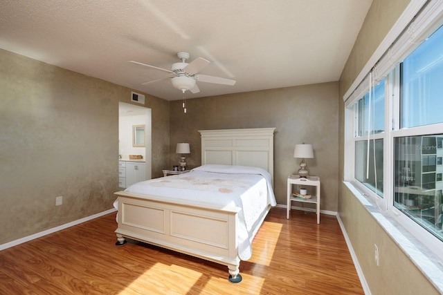 bedroom with visible vents, baseboards, light wood-type flooring, ensuite bathroom, and a ceiling fan