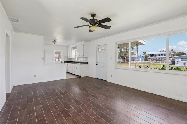 unfurnished living room with ceiling fan, visible vents, dark wood finished floors, and a sink