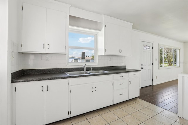 kitchen featuring dark countertops, white cabinetry, decorative backsplash, and a sink